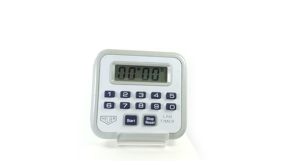 Chronomètre vintage HEUER ref. 750 - lab timer microsplit --- plan rapproché dans la main en vue de derrière --- ikonicstopwatch.com